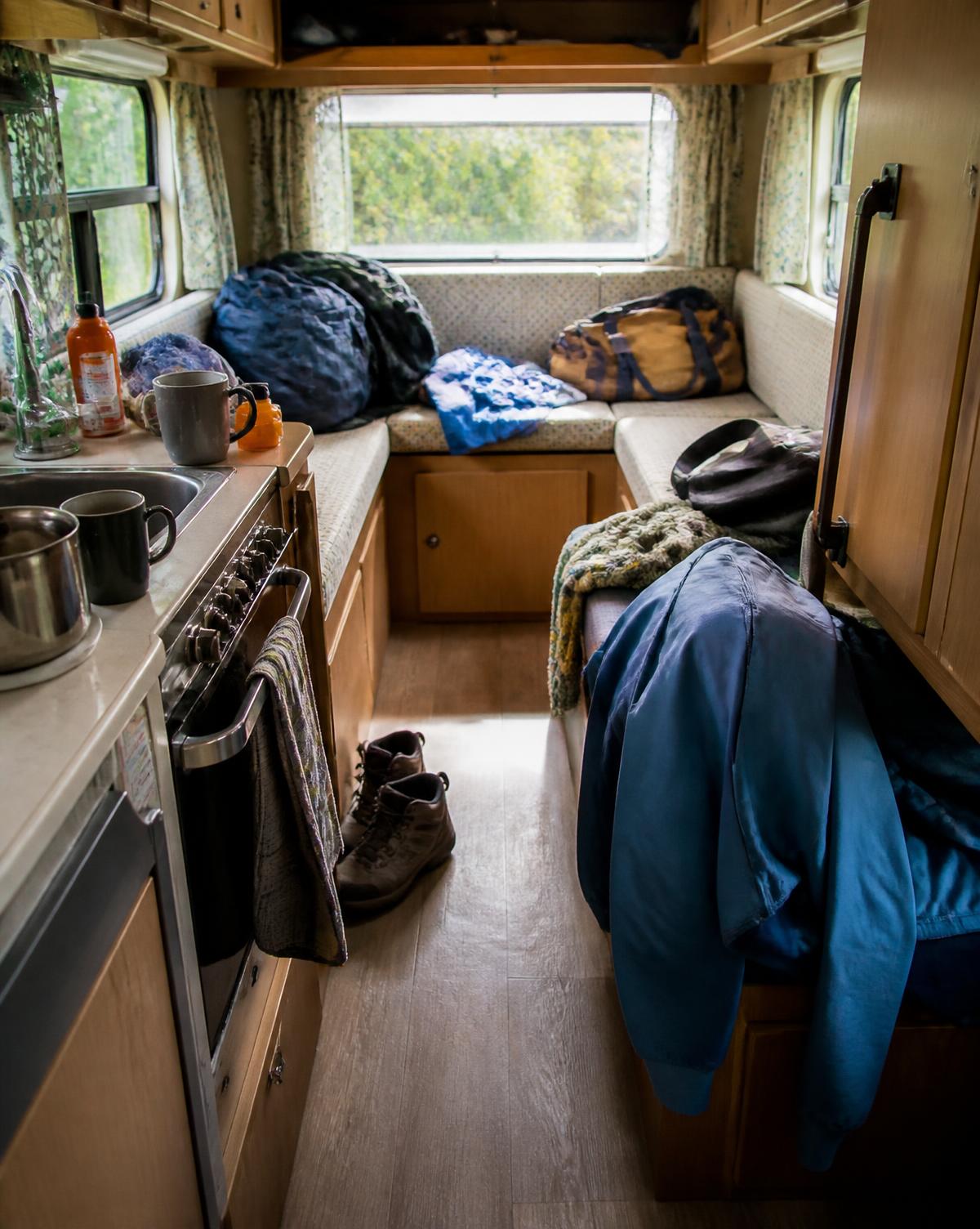Small camper interior with loose bags, jackets and shoes on the floor